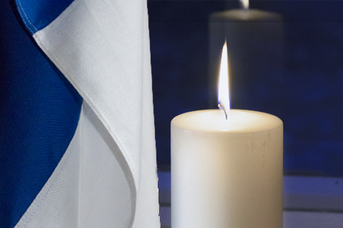 Suomen lippu ja valkoinen kynttilä.